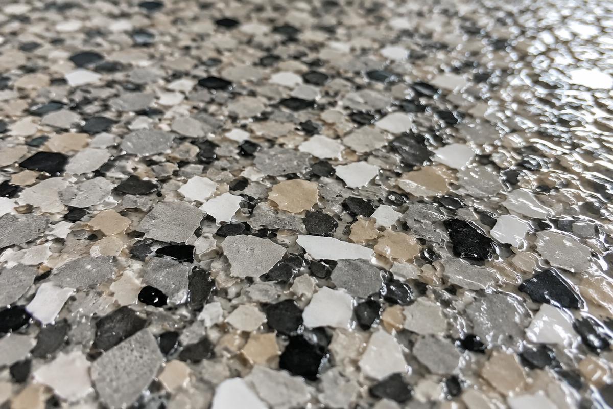 Close-up of gray, tan, black and white decorative flake chips under a clear glossy topcoat